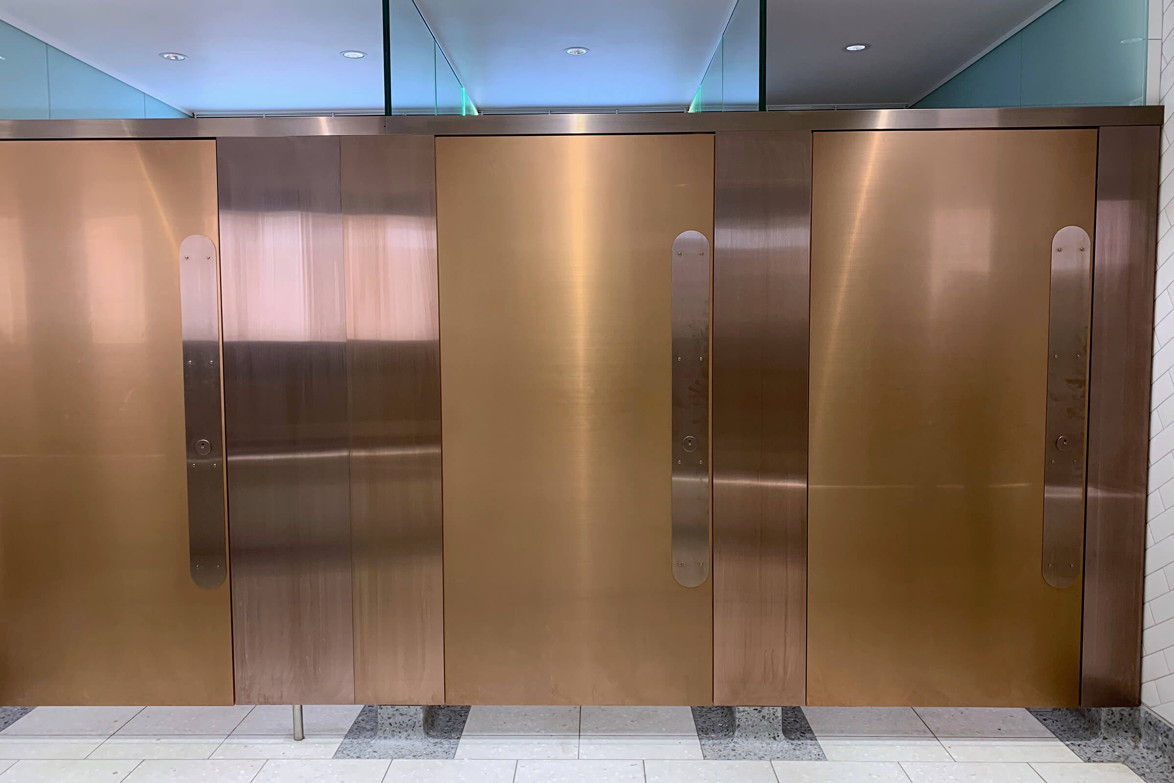 Toilet cubicles doors and partitions in PVD coloured stainless steel Rose Gold Hairline.
WCs upgrade, Victoria Station, London 
Client: Network Rail
Architects: Landolt + Brown
Fitout: Maxwood Washrooms
PVD coloured stainless steel by Double Stone Steel 
Architectural metalwork by John Desmond Ltd