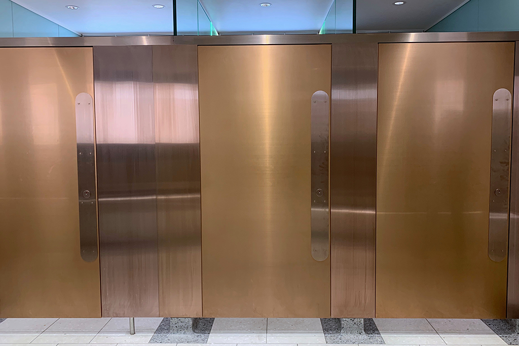 Cubicle doors & panels in PVD coloured stainless steel in Rose Gold Hairline, Victoria Station, London.